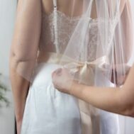 A seamstress tying a bow on a wedding dress